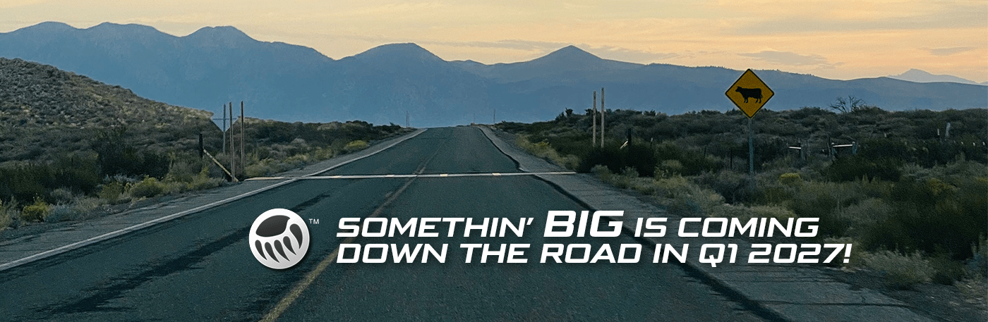 A deserted road stretches into the mountains, with a warning sign for cattle. Text announces a major event coming in 2027.